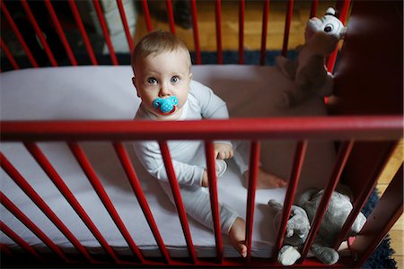 A 10 months baby boy sitting in his baby's cot Foto de stock - Con derechos protegidos, Código: 877-08079031