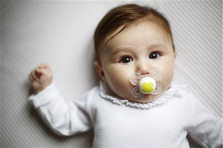 female body lying down - Portrait of 4 months baby girl with a dummy Photographie de stock - Rights-Managed, Code: 877-08079176