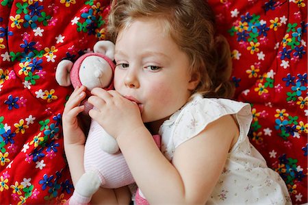 saugen - A 3 years old girl sucking his thumb, lying on her bed Foto de stock - Con derechos protegidos, Código: 877-08127966