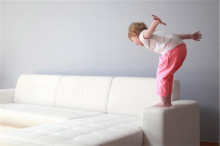 risco de acidente - France,  4 years old girl on sofa arm. Foto de stock - Direito Controlado, Número: 877-08127997