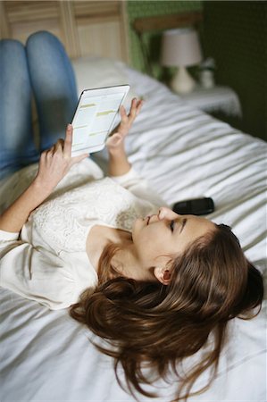 A teenage girl reading on a touch pad on her bed Stockbilder - Lizenzpflichtiges, Bildnummer: 877-08128017