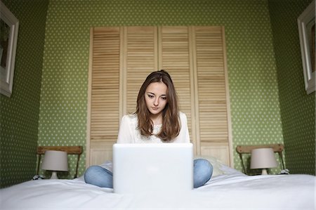 simsearch:877-08079201,k - A teenage gril consulting her laptop on her bed Foto de stock - Con derechos protegidos, Código: 877-08128013