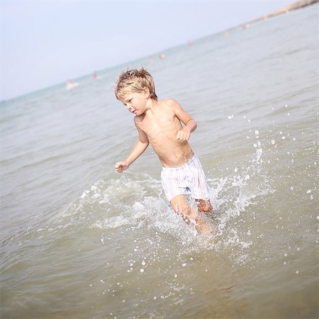 Little boy playing in the water at the beach Foto de stock - Con derechos protegidos, Código: 877-08128125