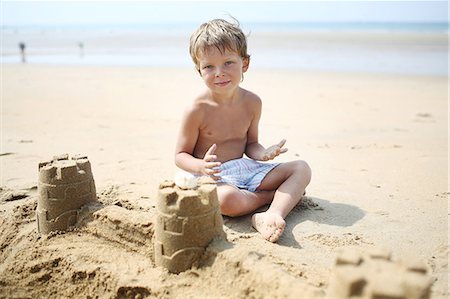 Little boy making a sand castle on the beach Foto de stock - Con derechos protegidos, Código: 877-08128131
