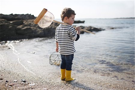 3 years old boy fishing with a net at the beach Foto de stock - Con derechos protegidos, Código: 877-08129112