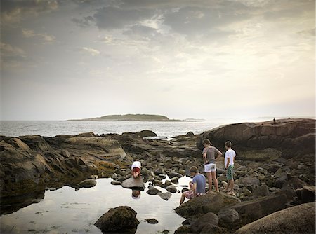 pozza di marea - A group of people on the shore, rock pooling, and exploring the marine life. View to an island offshore. Fotografie stock - Rights-Managed, Codice: 878-07442504