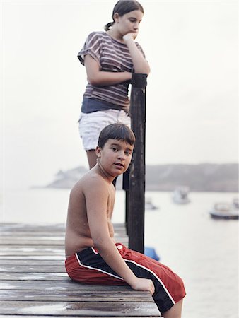 swim shorts for boys - Two young people, teenagers, boy and girl, on a dock overlooking moored boats on the coastline. Stock Photo - Rights-Managed, Code: 878-07442509