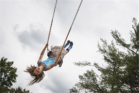 swinging - A girl on a rope swing, high in the air Foto de stock - Con derechos protegidos, Código: 878-07442516