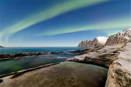 The Northern Lights and stars illuminate the rocky peaks and icy sea Tungeneset Senja Tromsø Norway Europe Photographie de stock - Rights-Managed, Code: 879-09021225