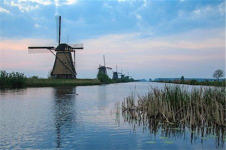 simsearch:6119-08541937,k - Blue sky and pink clouds on the windmills reflected in the canal at dawn Kinderdijk Rotterdam South Holland Netherlands Europe Foto de stock - Direito Controlado, Número: 879-09034155