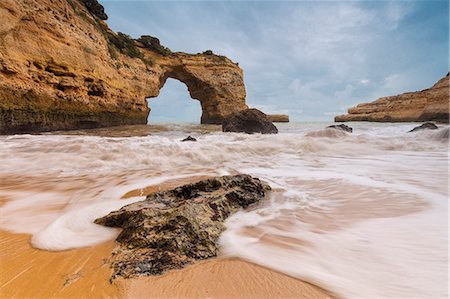 Waves crashing on the sand beach surrounded by cliffs Albandeira Lagoa Municipality Algarve Portugal Europe Photographie de stock - Rights-Managed, Code: 879-09034355