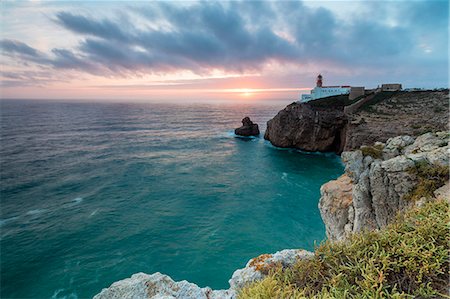 Pink sky at sunset frames the lighthouse overlooking the Atlantic Ocean Cabo De Sao Vicente Sagres Algarve Portugal Europe Stock Photo - Rights-Managed, Code: 879-09034359