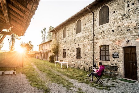 simsearch:879-09034416,k - Grazzano Visconti, Vigolzone, Piacenza district, Emilia Romagna, Italy. Woman reading on a chair in a old couryard of the town. Foto de stock - Con derechos protegidos, Código: 879-09033535