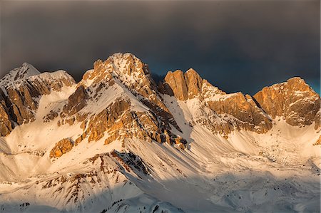 simsearch:879-09129121,k - A fiery winter sunset towards the Sasso di Valfredda. From the left Punta Jigole, Sasso Vernale, Cima Ombrettola, Sasso Valfredda and Formenton. Behind them, covered by clouds the immense south face of the Marmolada. Dolomites, Italy Photographie de stock - Rights-Managed, Code: 879-09033670