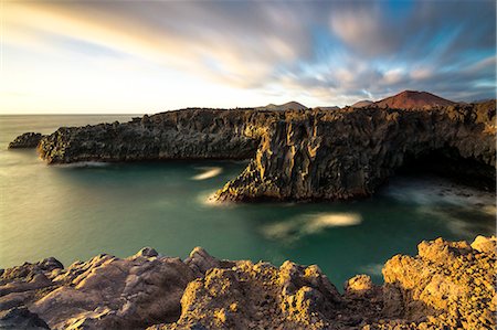simsearch:6129-09057915,k - Los Hervideros - Yaiza,Lanzarote Los hervideros is characterized by rocky cliffs overlooking the Atlantic and in the background the volcanoes Stock Photo - Rights-Managed, Code: 879-09033706