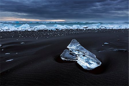 The black beach of Jokulsarlon at low tide is filled with small ice floes that contrast with the dark ground. Stock Photo - Rights-Managed, Code: 879-09043685