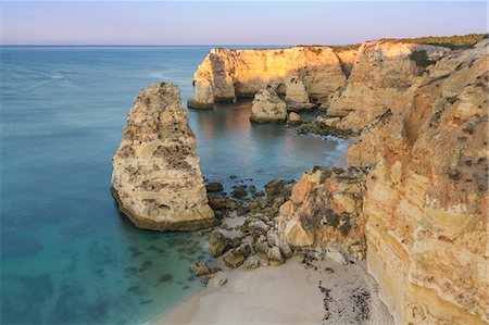 Sunrise on the cliffs and turquoise water of the ocean Praia da Marinha Caramujeira Lagoa Municipality Algarve Portugal Europe Foto de stock - Con derechos protegidos, Código: 879-09043895