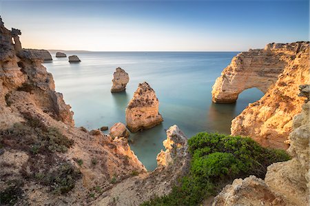 Sunrise on the cliffs and turquoise water of the ocean Praia da Marinha Caramujeira Lagoa Municipality Algarve Portugal Europe Photographie de stock - Rights-Managed, Code: 879-09043896