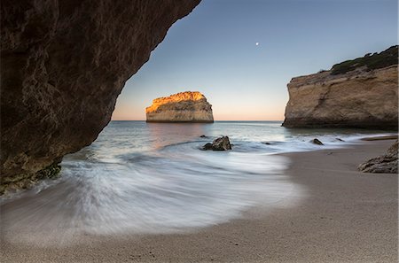 A sea cave frames the beach of Praia De Albandeira at dawn Carvoeiro Caramujeira Lagoa Municipality Algarve Portugal Europe Foto de stock - Direito Controlado, Número: 879-09043905