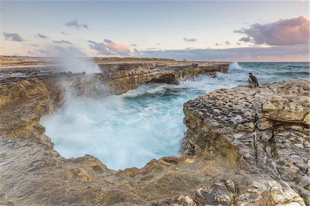 simsearch:879-09190975,k - Hiker on the cliffs admires the crashing waves at Devil's Bridge Caribbean Antigua and Barbuda Leeward Islands West Indies Photographie de stock - Rights-Managed, Code: 879-09043916