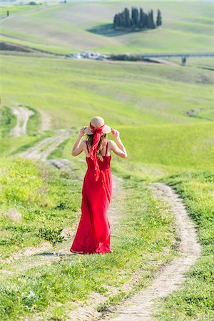 simsearch:879-09100804,k - San Quirico d'Orcia, Orcia valley, Siena, Tuscany, Italy. A young woman in red dress walking along a country path near the cypresses of val d'orcia Stock Photo - Rights-Managed, Code: 879-09099966