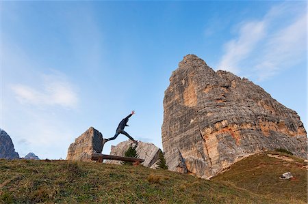 A hiker jumps in fornt of Cinque Torri, Dolomites, Cortina d'Ampezzo, Belluno province, Veneto, Italy Stock Photo - Rights-Managed, Code: 879-09100128