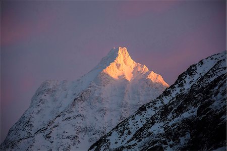 The pink light of sunrise illuminates the snowy peaks of the rocky mountains Svensby Lyngen Alps Tromsø Norway Europe Photographie de stock - Rights-Managed, Code: 879-09100838