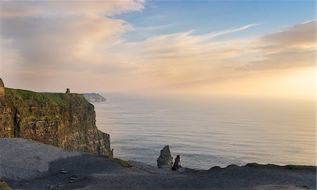 simsearch:6129-09057790,k - Cliffs of Moher, Liscannor, Co. Clare, Munster province, Ireland. A woman watch the sunset sitting on a rock. Foto de stock - Con derechos protegidos, Código: 879-09128834