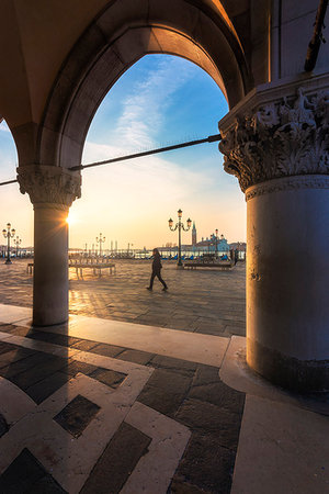 san giorgio maggiore - A man walking under the arches of Palazzo Ducale, in the background the monastery of San Giorgio Maggiore,Venice, Veneto, Italy Fotografie stock - Rights-Managed, Codice: 879-09189235