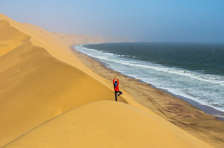 simsearch:700-07067208,k - Man take yoga tree pose from the top of the sand dunes,Sandwich Harbour,Namib Naukluft National Park,Namibia,Africa Photographie de stock - Rights-Managed, Code: 879-09189767