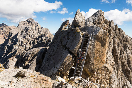 a climber is get on a stair along the ridge of the via ferrata Bepi Zac into the Marmolada Group and on the battlefront of the World War One, Trento Province, Trentino Alto Adige, Italy Stockbilder - Lizenzpflichtiges, Bildnummer: 879-09190543