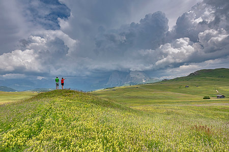 Alpe di Siusi/Seiser Alm, Dolomites, South Tyrol, Italy. Children look at storm clouds over Sassolungo Stock Photo - Rights-Managed, Code: 879-09190743