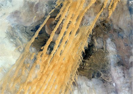 simsearch:872-06053962,k - Desert Erg Iguidi, Algeria, True Colour Satellite Image. True colour satellite image of Erg Iguidi, a sand desert between Algeria and Mauritania. The 250m wide dunes lay in the South on a sand plain, and in the North on a blakek sandstone area. The light blue areas are calcareous and salt crusts left out from the evaporation of the oueds' water. Image taken on 29 March 1987 using LANDSAT data. Foto de stock - Direito Controlado, Número: 872-06052991