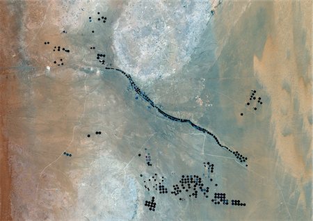 satellite view city - Agriculture In The Desert In 2001, Saudi Arabia, True Colour Satellite Image. True colour satellite image of agriculture in the desert, about 250 km west of the Saudi capital, Riyadh. Circular agricultural plots are visible on the image. Composite image taken in 2001, using LANDSAT 5 data. Stock Photo - Rights-Managed, Code: 872-06053954