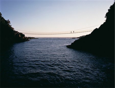 Silhouette of People Crossing Storms River Gorge on Rope Bridge South Africa Fotografie stock - Rights-Managed, Codice: 873-06440408