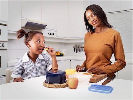 Mother with daughter (6-7) in kitchen, girl eating Stock Photo - Rights-Managed, Code: 873-06675492