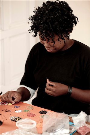 simsearch:873-06675608,k - Young African woman doing beadwork at a desk Fotografie stock - Rights-Managed, Codice: 873-06675600