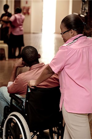 simsearch:873-06675608,k - Nurse pushing African man in a wheelchair Fotografie stock - Rights-Managed, Codice: 873-06675613